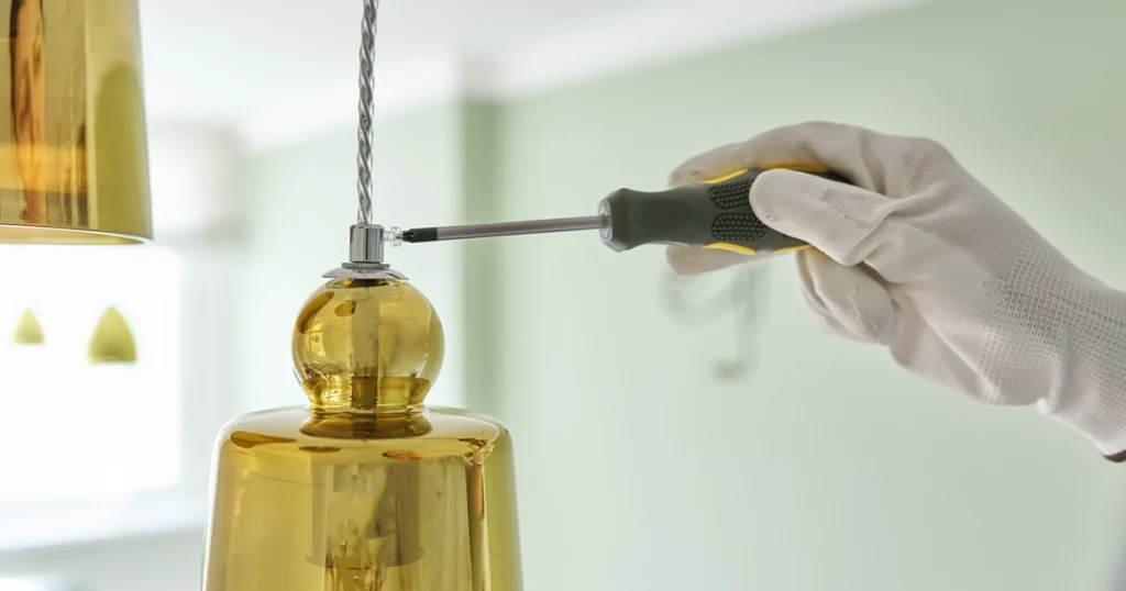 Rewiring a lamp with screwdriver and gloves in a home setting